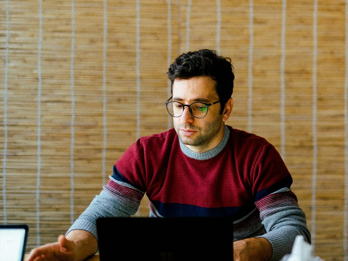 اپراتور پشت میز کار، متمرکز روی لپ‌تاپ باز
